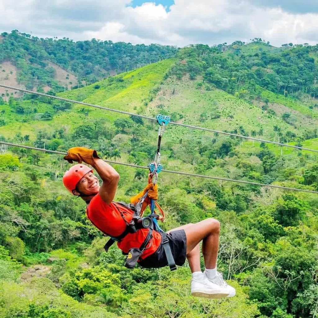 Man zip-lining through lush greenery in Bayahibe, enjoying an adventurous outdoor activity.