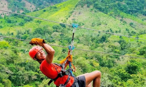 Man zip-lining through lush greenery in Bayahibe, enjoying an adventurous outdoor activity.
